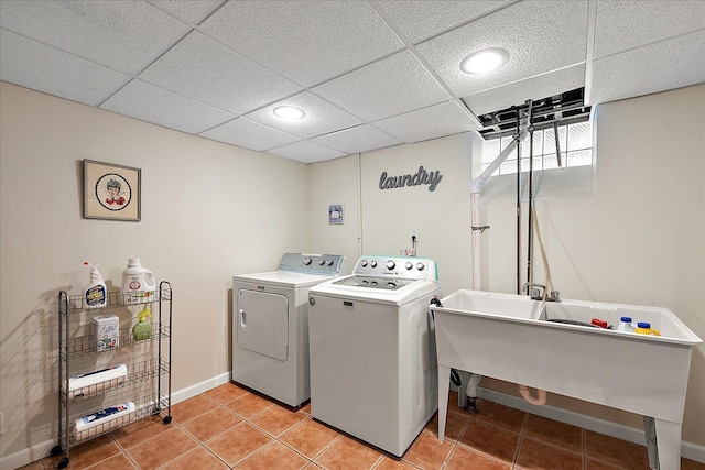 clothes washing area with laundry area, baseboards, separate washer and dryer, a sink, and light tile patterned floors