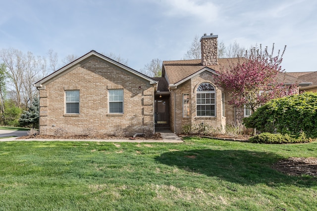 single story home featuring brick siding, a chimney, and a front yard