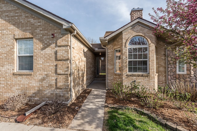 doorway to property with brick siding and a chimney