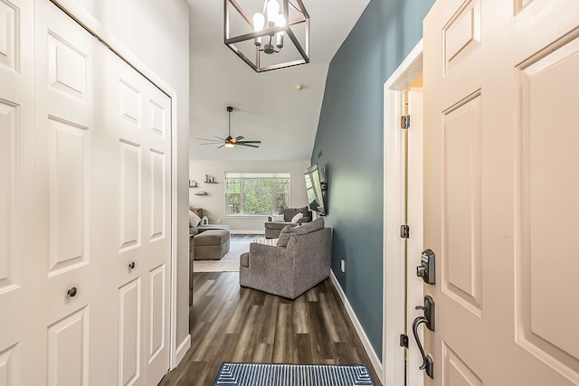 foyer featuring dark wood-type flooring, baseboards, ceiling fan with notable chandelier, and vaulted ceiling