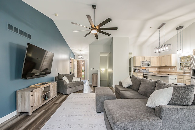 living area featuring visible vents, baseboards, high vaulted ceiling, dark wood-type flooring, and a ceiling fan