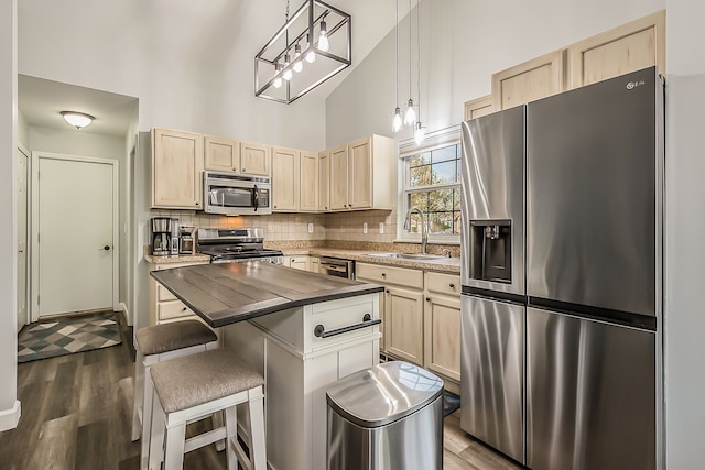 kitchen featuring dark wood-style flooring, light brown cabinetry, a sink, high vaulted ceiling, and stainless steel appliances