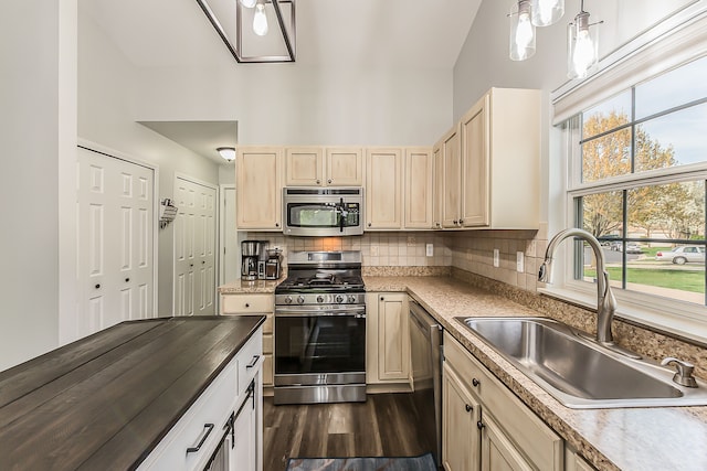 kitchen with decorative backsplash, light brown cabinetry, dark wood-style floors, a sink, and stainless steel appliances