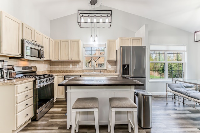 kitchen featuring a sink, appliances with stainless steel finishes, dark wood-style floors, and a breakfast bar