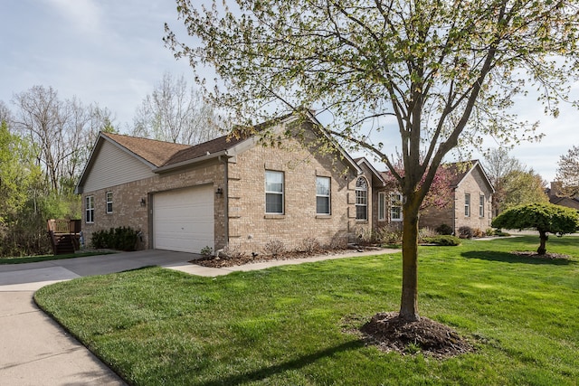 view of side of property with a yard, brick siding, driveway, and a garage
