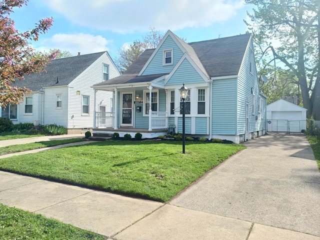bungalow-style home with a shingled roof, a front lawn, a detached garage, a porch, and an outbuilding