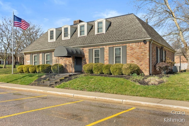 2464 Abbington Dr SE, Grand Rapids, MI 49506 - cape cod house with brick siding, a front yard, cooling unit, and roof with shingles