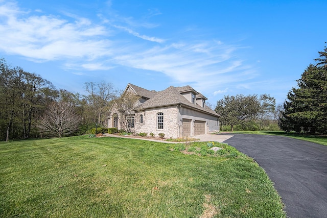 view of side of property featuring a yard, brick siding, stone siding, and aphalt driveway