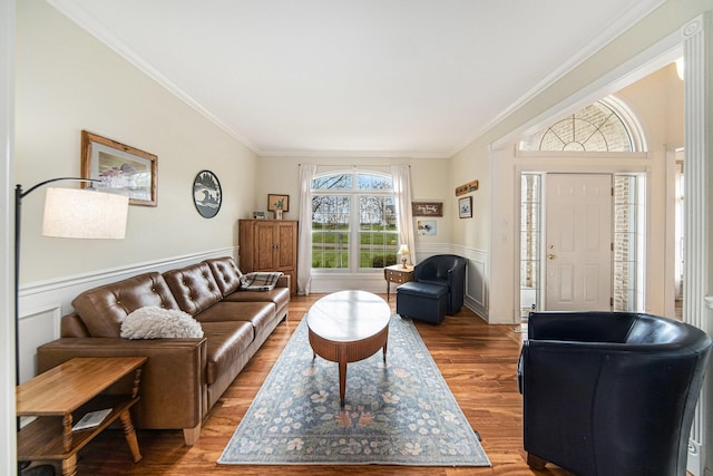 living area featuring ornamental molding, light wood finished floors, and a wainscoted wall