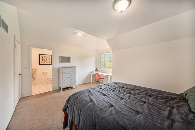 bedroom featuring visible vents, baseboards, light colored carpet, ensuite bath, and vaulted ceiling