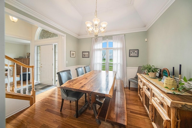 dining area with wood finished floors, stairway, a wainscoted wall, a notable chandelier, and ornamental molding