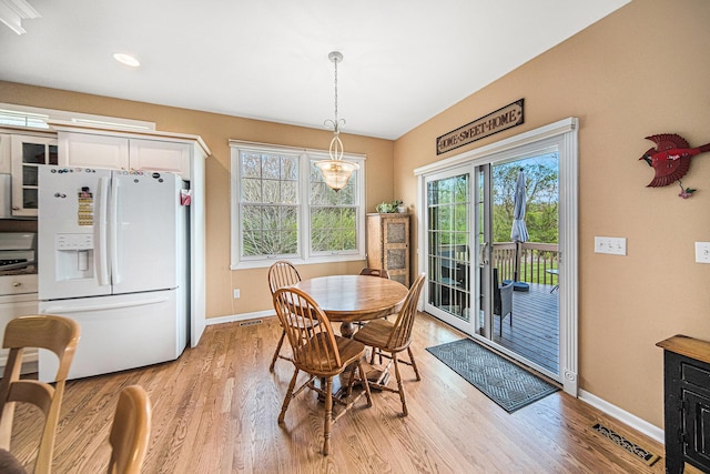 dining area featuring baseboards, visible vents, and light wood finished floors
