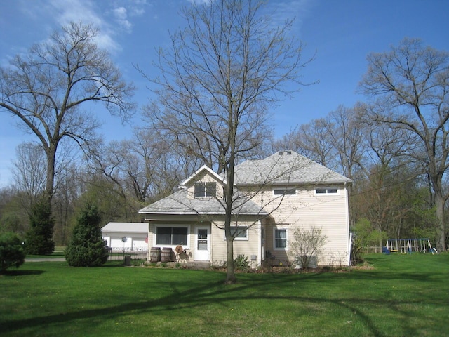 rear view of house with a lawn and a playground