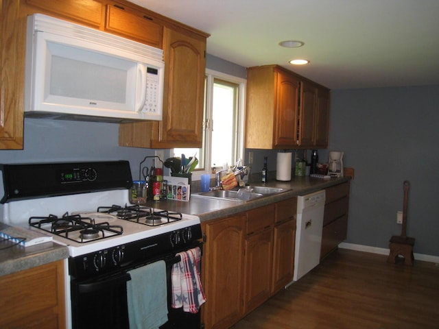 kitchen featuring white appliances, brown cabinets, dark wood-style floors, and a sink