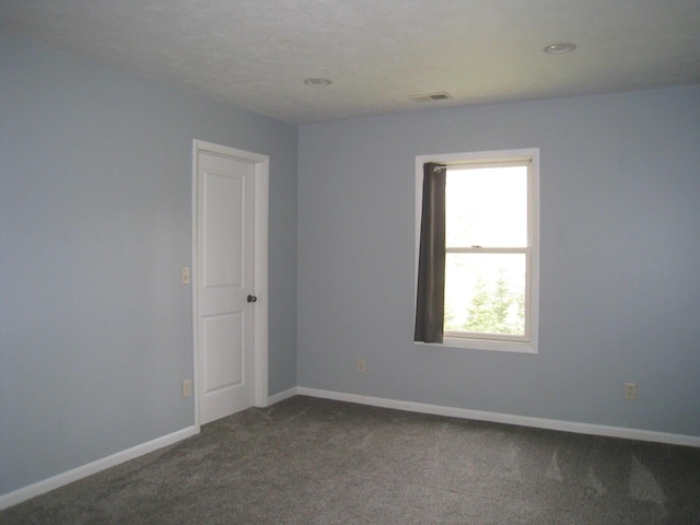 empty room featuring dark colored carpet, recessed lighting, and baseboards