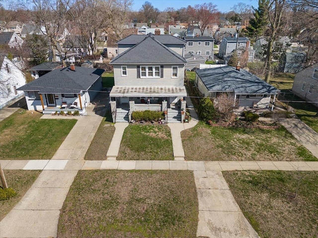 exterior space with a porch, roof with shingles, a residential view, a front lawn, and concrete driveway