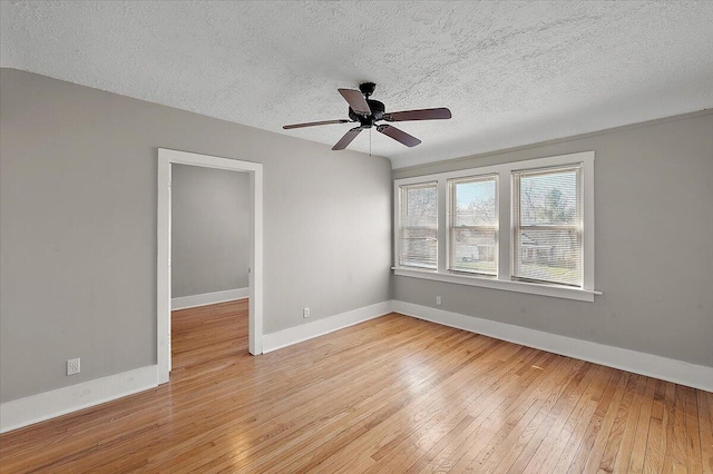 unfurnished room with baseboards, a textured ceiling, and light wood finished floors