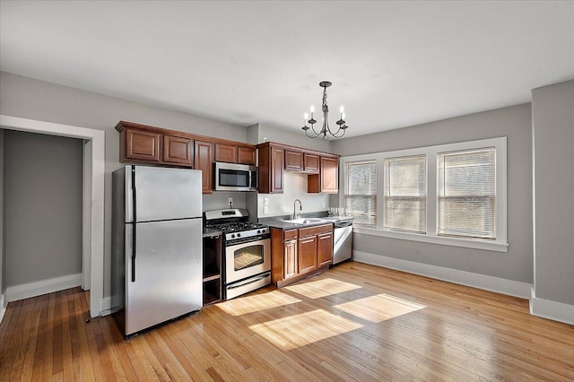 kitchen featuring decorative light fixtures, baseboards, a chandelier, stainless steel appliances, and light wood-style flooring
