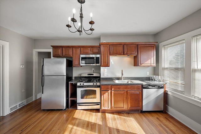kitchen featuring visible vents, appliances with stainless steel finishes, dark countertops, a sink, and baseboards