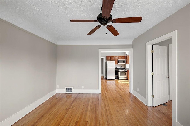 spare room with light wood-type flooring, baseboards, ceiling fan, and visible vents