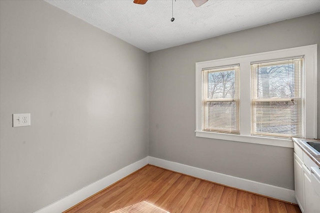 spare room featuring a textured ceiling, baseboards, ceiling fan, and light wood-type flooring