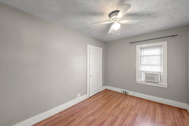 spare room featuring baseboards, ceiling fan, cooling unit, and light wood finished floors