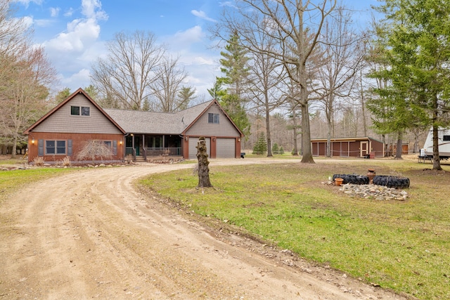 view of front of home featuring a garage, dirt driveway, a front lawn, and covered porch