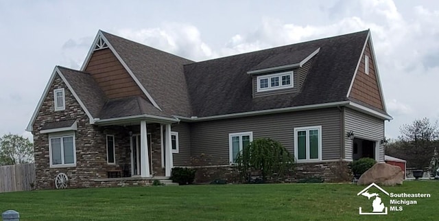 view of front facade with a front lawn, roof with shingles, fence, and stone siding