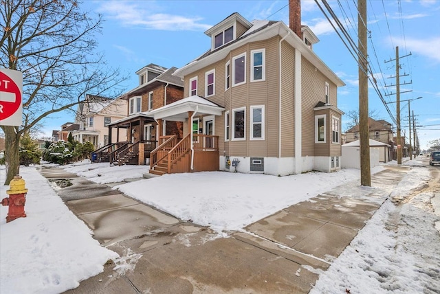 american foursquare style home featuring a residential view, an outbuilding, and a porch