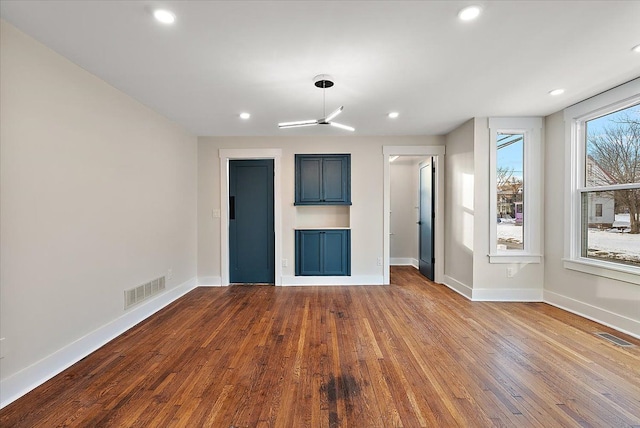 unfurnished living room with visible vents, baseboards, and dark wood-type flooring