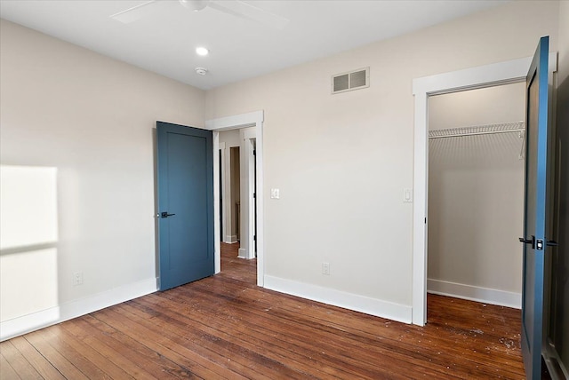 unfurnished bedroom with a closet, baseboards, visible vents, and hardwood / wood-style flooring