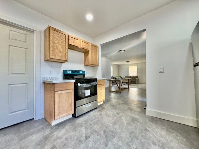 kitchen with light countertops, baseboards, and stainless steel range with gas cooktop