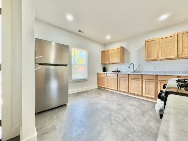 kitchen featuring visible vents, freestanding refrigerator, light brown cabinets, and light countertops
