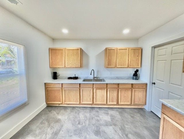 kitchen featuring light countertops, recessed lighting, light colored carpet, and a sink