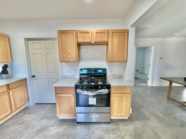 kitchen featuring light countertops, baseboards, concrete floors, and gas range
