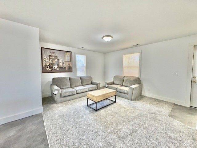 living room featuring baseboards, carpet flooring, and visible vents