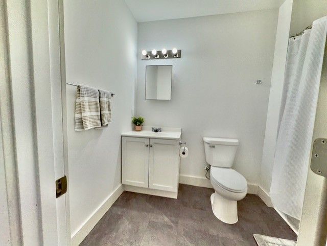 bathroom with baseboards, vanity, toilet, and curtained shower