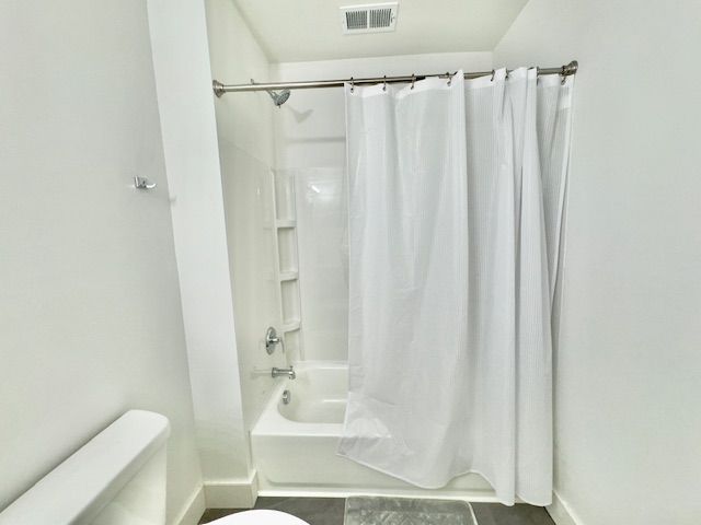 full bathroom featuring tile patterned flooring, toilet, shower / bath combo with shower curtain, baseboards, and visible vents
