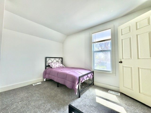 bedroom featuring baseboards, carpet, vaulted ceiling, and visible vents