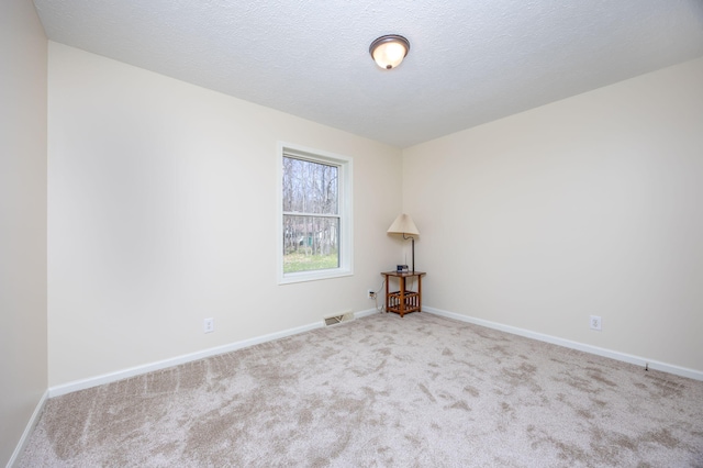 spare room with carpet floors, baseboards, and visible vents