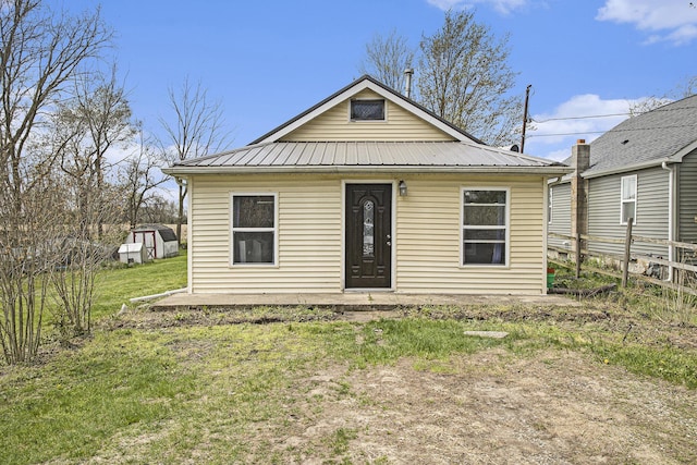 rear view of house featuring a lawn, fence, an outbuilding, and metal roof
