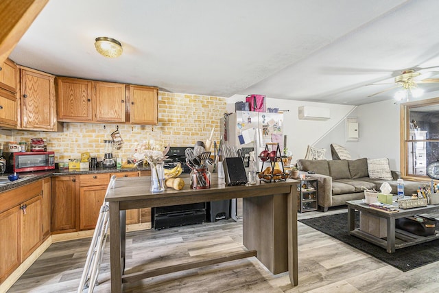 kitchen featuring ceiling fan, a wall unit AC, dark countertops, light wood finished floors, and refrigerator with ice dispenser