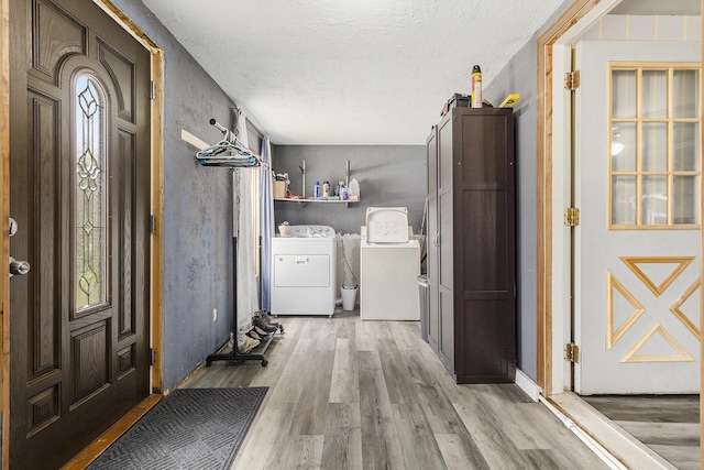 interior space featuring a textured ceiling, baseboards, washing machine and dryer, and wood finished floors