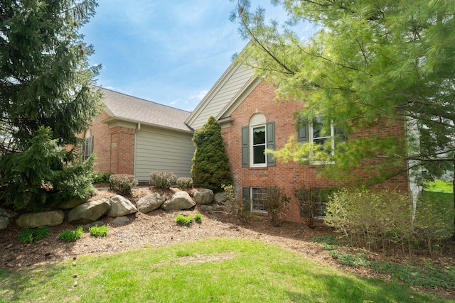 view of side of property featuring brick siding and a lawn