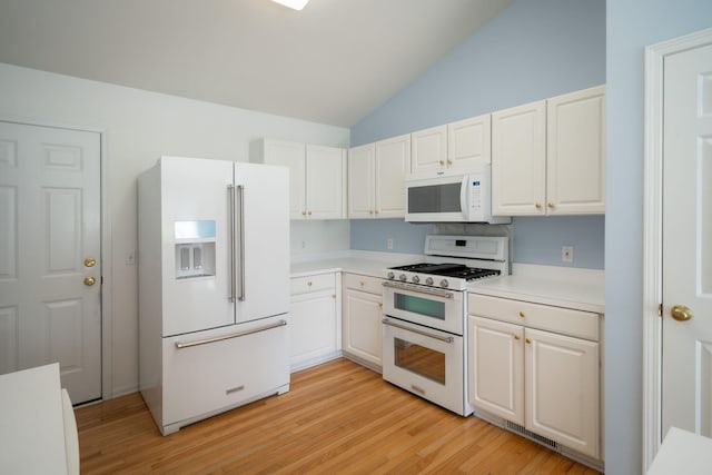 kitchen with white appliances, light wood-style floors, light countertops, white cabinets, and vaulted ceiling