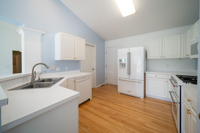 kitchen featuring a sink, light wood finished floors, lofted ceiling, white appliances, and white cabinetry