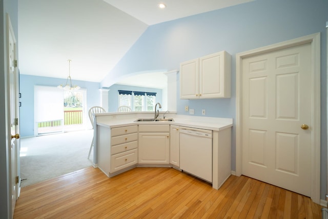 kitchen featuring dishwasher, a sink, light wood finished floors, a peninsula, and a chandelier