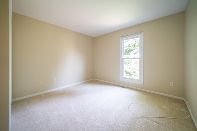 spare room featuring visible vents, baseboards, and light carpet