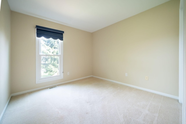 spare room with light colored carpet, baseboards, and visible vents