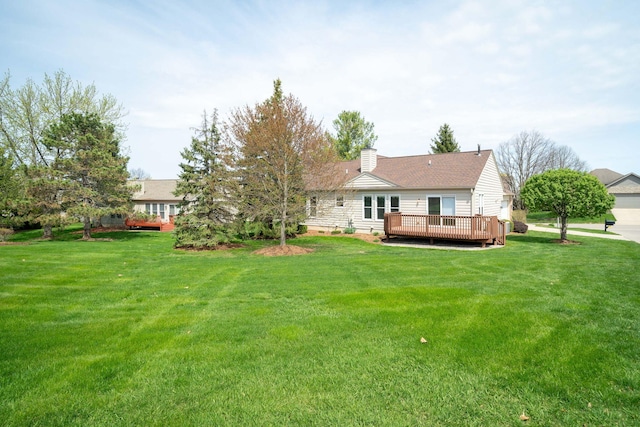 back of house with a chimney, a yard, and a deck
